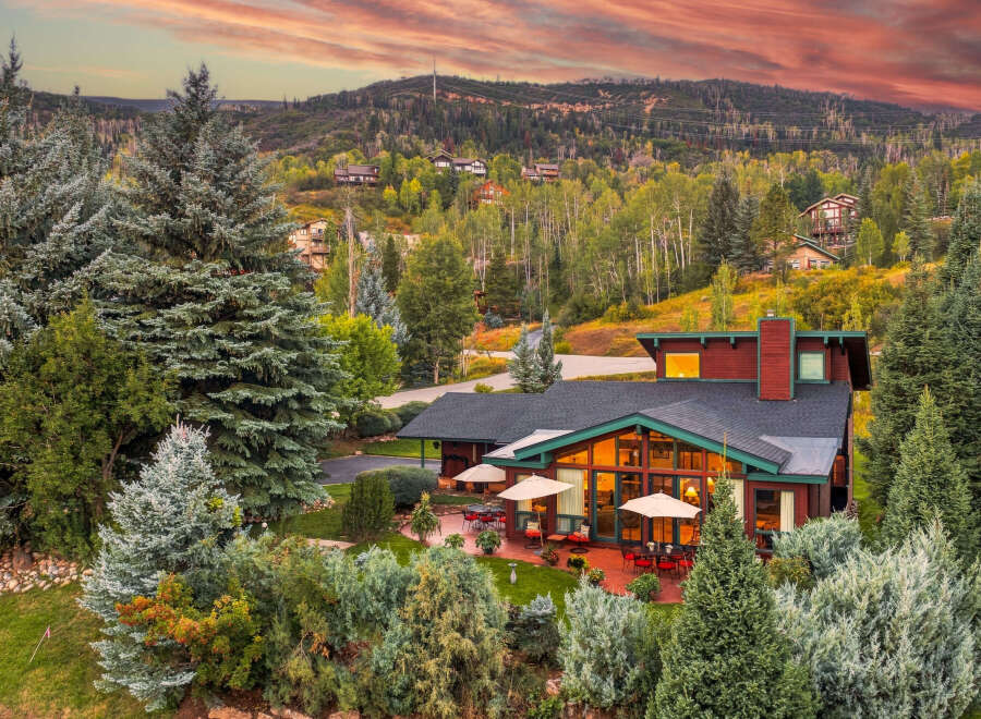 Experience luxurious mountain living in this stunning home nestled amidst a vibrant autumn landscape.