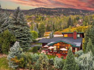 Experience luxurious mountain living in this stunning home nestled amidst a vibrant autumn landscape.