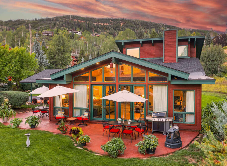 Experience luxury mountain living with this stunning property featuring a spacious patio perfect for entertaining, complete with a grill and outdoor dining sets.