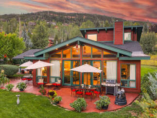 Experience luxury mountain living with this stunning property featuring a spacious patio perfect for entertaining, complete with a grill and outdoor dining sets.
