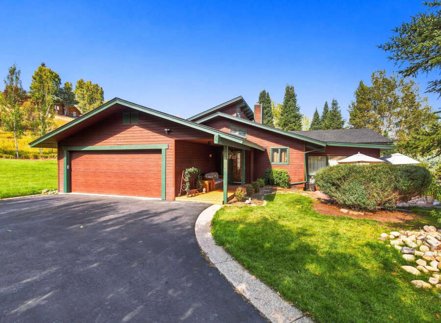 Nestled amidst lush greenery and mature trees, this charming red wood-sided home offers a serene retreat.