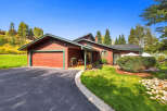 Nestled amidst lush greenery and mature trees, this charming red wood-sided home offers a serene retreat.