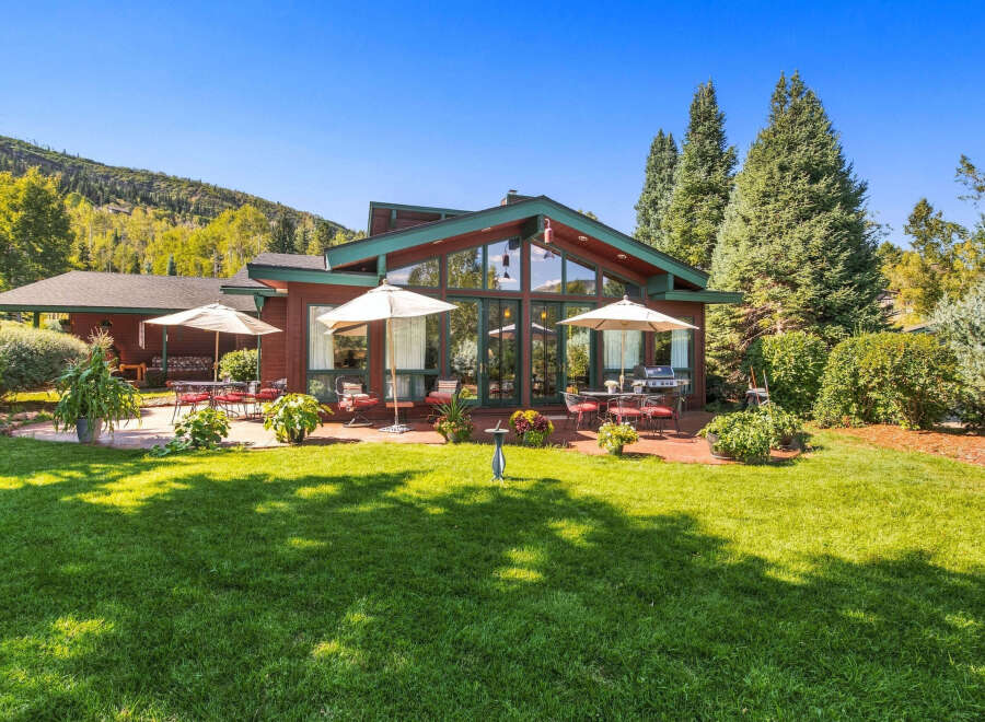 Enjoy outdoor living in this charming home featuring a spacious patio with seating and umbrellas, perfect for al fresco dining.
