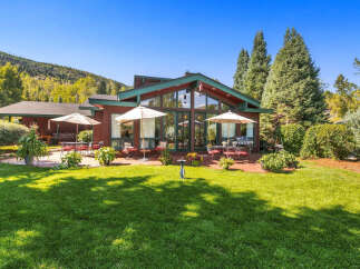Enjoy outdoor living in this charming home featuring a spacious patio with seating and umbrellas, perfect for al fresco dining.