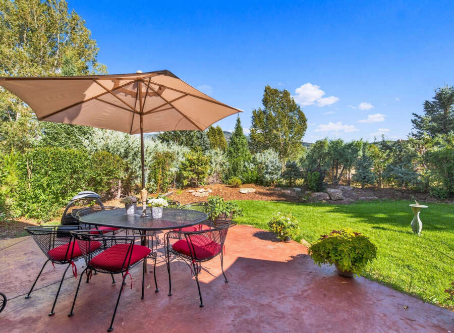 Enjoy outdoor living with this charming patio featuring a wrought iron dining set and umbrella, perfect for al fresco meals.
