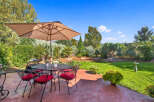 Enjoy outdoor living with this charming patio featuring a wrought iron dining set and umbrella, perfect for al fresco meals.