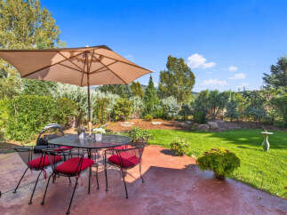Enjoy outdoor living with this charming patio featuring a wrought iron dining set and umbrella, perfect for al fresco meals.