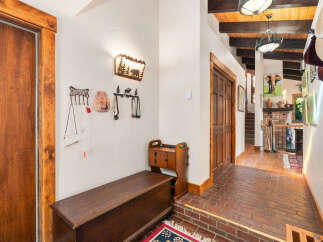 Step into a warm and inviting entryway featuring rustic wooden doors and a charming bench for seating.