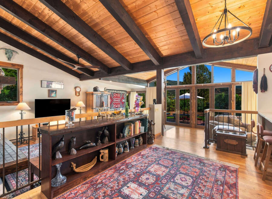 Experience rustic charm and breathtaking views in this stunning living space, featuring a vaulted wood-beam ceiling and expansive windows that flood the room with natural light.