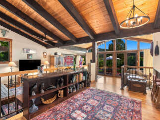 Experience rustic charm and breathtaking views in this stunning living space, featuring a vaulted wood-beam ceiling and expansive windows that flood the room with natural light.