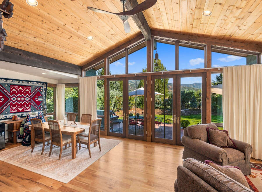 Experience breathtaking mountain views from this stunning living space, featuring a vaulted wood-paneled ceiling and expansive windows.