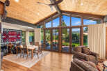Experience breathtaking mountain views from this stunning living space, featuring a vaulted wood-paneled ceiling and expansive windows.