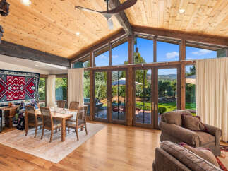 Experience breathtaking mountain views from this stunning living space, featuring a vaulted wood-paneled ceiling and expansive windows.