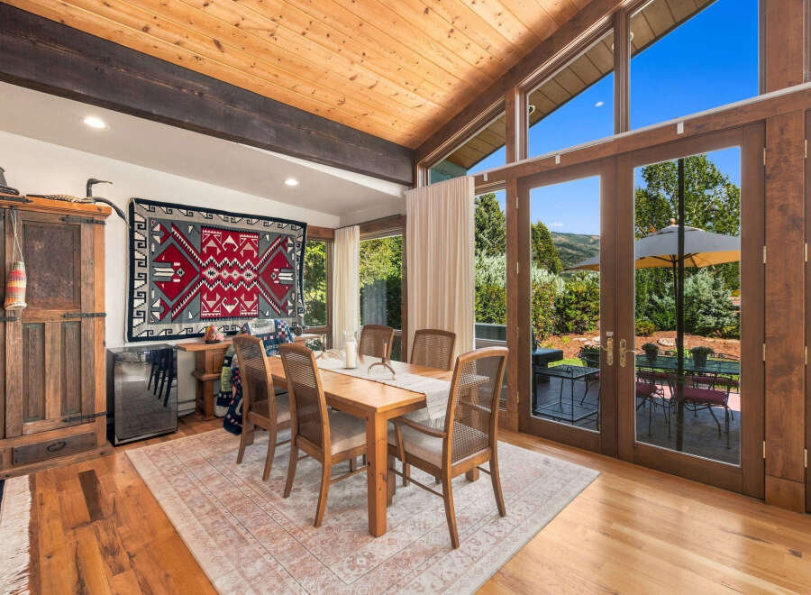 Experience breathtaking mountain views from this stunning dining room, featuring a vaulted wood-beamed ceiling and expansive windows that flood the space with natural light.