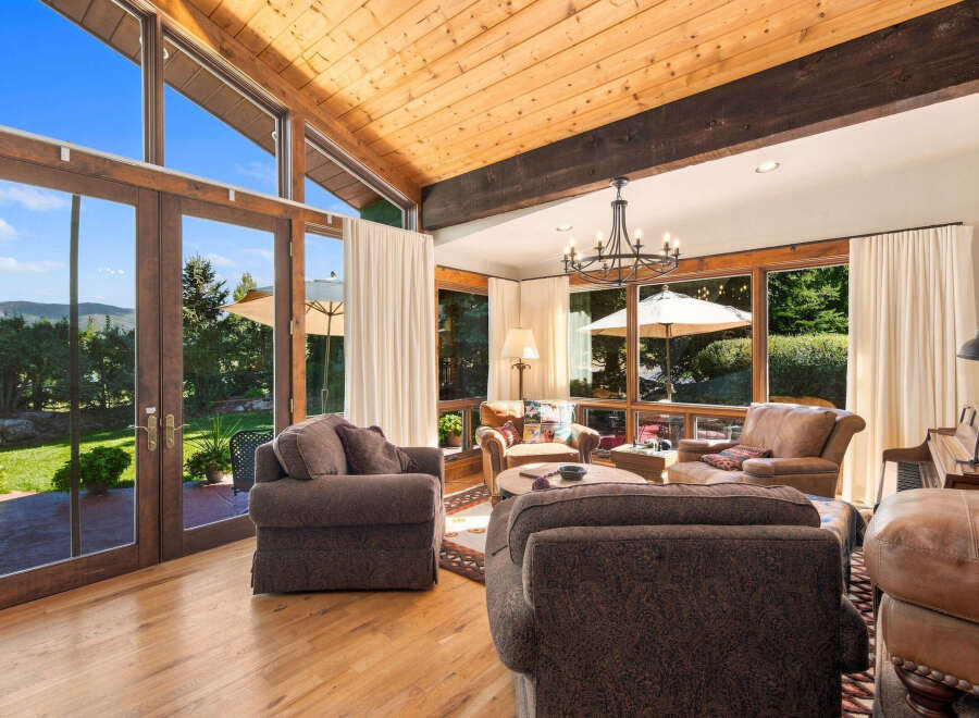 Experience breathtaking mountain views from this stunning living room, featuring soaring vaulted ceilings with exposed wood beams and expansive windows that flood the space with natural light.