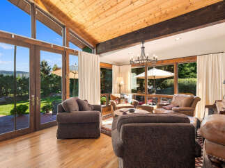 Experience breathtaking mountain views from this stunning living room, featuring soaring vaulted ceilings with exposed wood beams and expansive windows that flood the space with natural light.