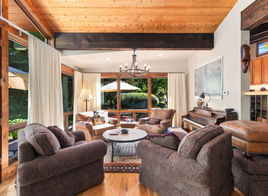 Experience the warmth of this inviting living room, featuring a stunning wood-beamed ceiling and expansive windows that flood the space with natural light.