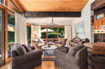 Experience the warmth of this inviting living room, featuring a stunning wood-beamed ceiling and expansive windows that flood the space with natural light.