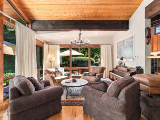 Experience the warmth of this inviting living room, featuring a stunning wood-beamed ceiling and expansive windows that flood the space with natural light.