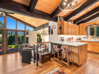 Experience breathtaking mountain views from this stunning home featuring a vaulted wood-beamed ceiling and expansive windows.