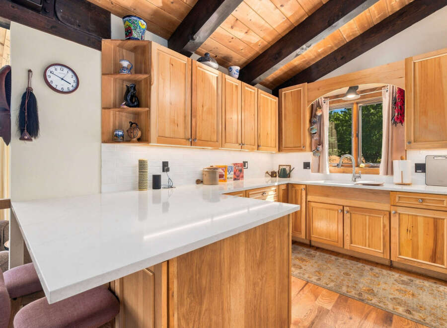 This charming kitchen boasts beautiful natural wood cabinetry and a spacious quartz countertop island, perfect for meal preparation and casual dining.