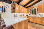 This charming kitchen boasts beautiful natural wood cabinetry and a spacious quartz countertop island, perfect for meal preparation and casual dining.