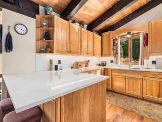 This charming kitchen boasts beautiful natural wood cabinetry and a spacious quartz countertop island, perfect for meal preparation and casual dining.