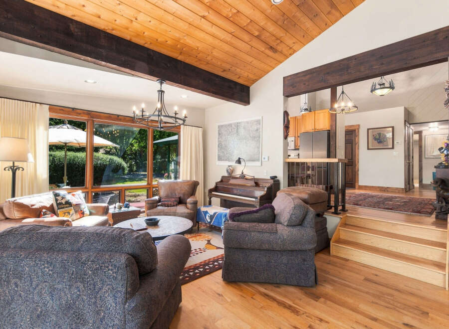 Experience rustic charm in this inviting living room, featuring a vaulted wood-paneled ceiling with exposed beams and a grand stone fireplace.