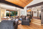 Experience rustic charm in this inviting living room, featuring a vaulted wood-paneled ceiling with exposed beams and a grand stone fireplace.