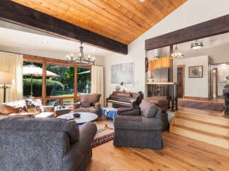 Experience rustic charm in this inviting living room, featuring a vaulted wood-paneled ceiling with exposed beams and a grand stone fireplace.