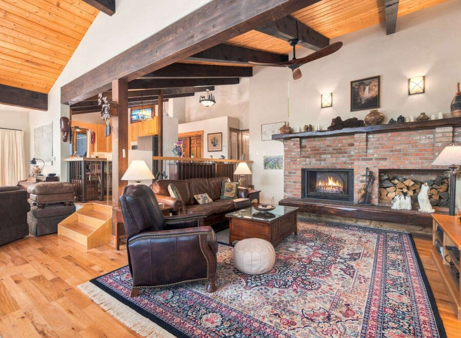 Experience rustic charm in this spacious living room featuring a grand brick fireplace and exposed wooden beams.