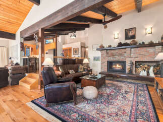 Experience rustic charm in this spacious living room featuring a grand brick fireplace and exposed wooden beams.