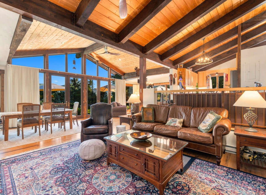 Experience rustic charm in this spacious living area, featuring a vaulted wood-beamed ceiling and expansive windows that flood the space with natural light.