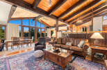 Experience rustic charm in this spacious living area, featuring a vaulted wood-beamed ceiling and expansive windows that flood the space with natural light.