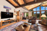 Experience rustic charm and breathtaking views in this spacious living area, featuring a vaulted wood-beamed ceiling and expansive windows that flood the room with natural light.