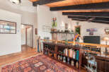 Experience rustic charm in this spacious living area featuring a vaulted wood-beamed ceiling and a cozy brick fireplace.