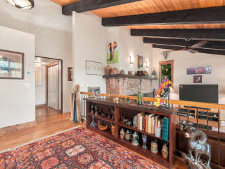 Experience rustic charm in this spacious living area featuring a vaulted wood-beamed ceiling and a cozy brick fireplace.