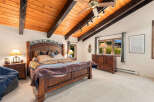 Experience rustic charm in this inviting bedroom, featuring a grand wooden bed with a decorative headboard and a cozy, patterned quilt.