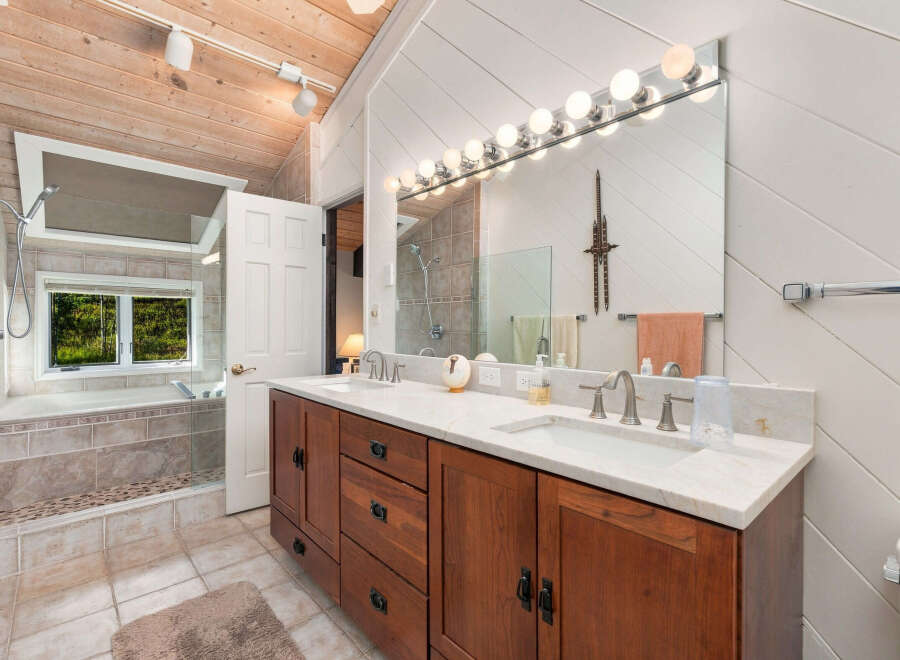 Experience luxury in this spacious bathroom featuring a deep soaking tub with a scenic window view and a double vanity with ample counter space.