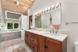 Experience luxury in this spacious bathroom featuring a deep soaking tub with a scenic window view and a double vanity with ample counter space.
