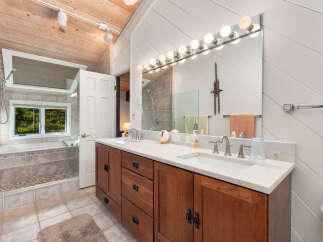 Experience luxury in this spacious bathroom featuring a deep soaking tub with a scenic window view and a double vanity with ample counter space.