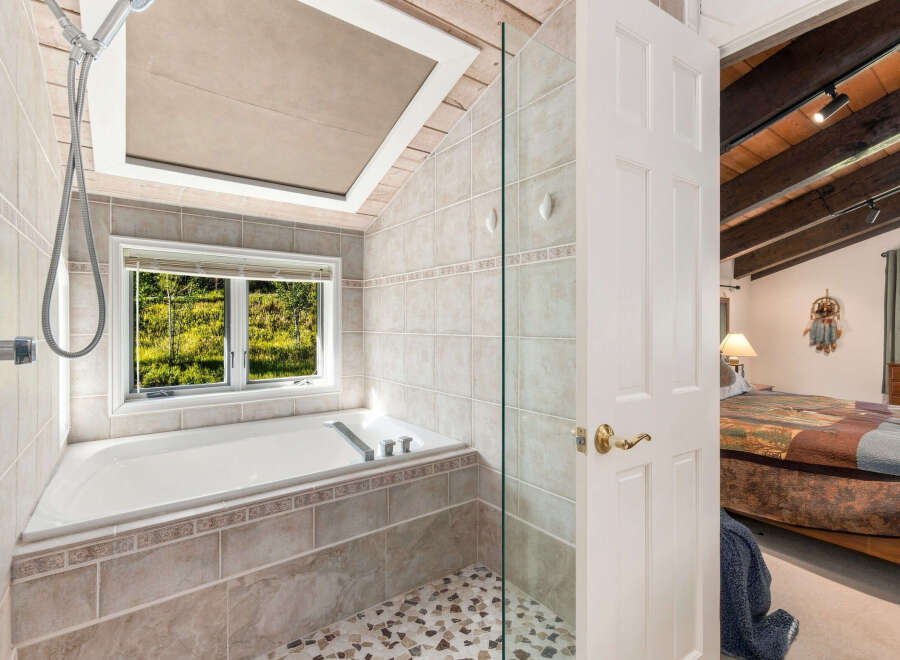 Experience ultimate relaxation in this luxurious bathroom featuring a deep soaking tub with a scenic window view and a separate shower area.