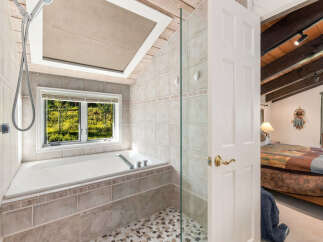 Experience ultimate relaxation in this luxurious bathroom featuring a deep soaking tub with a scenic window view and a separate shower area.