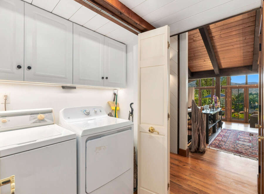 Discover a functional laundry area featuring white cabinetry and appliances, perfect for keeping chores organized.
