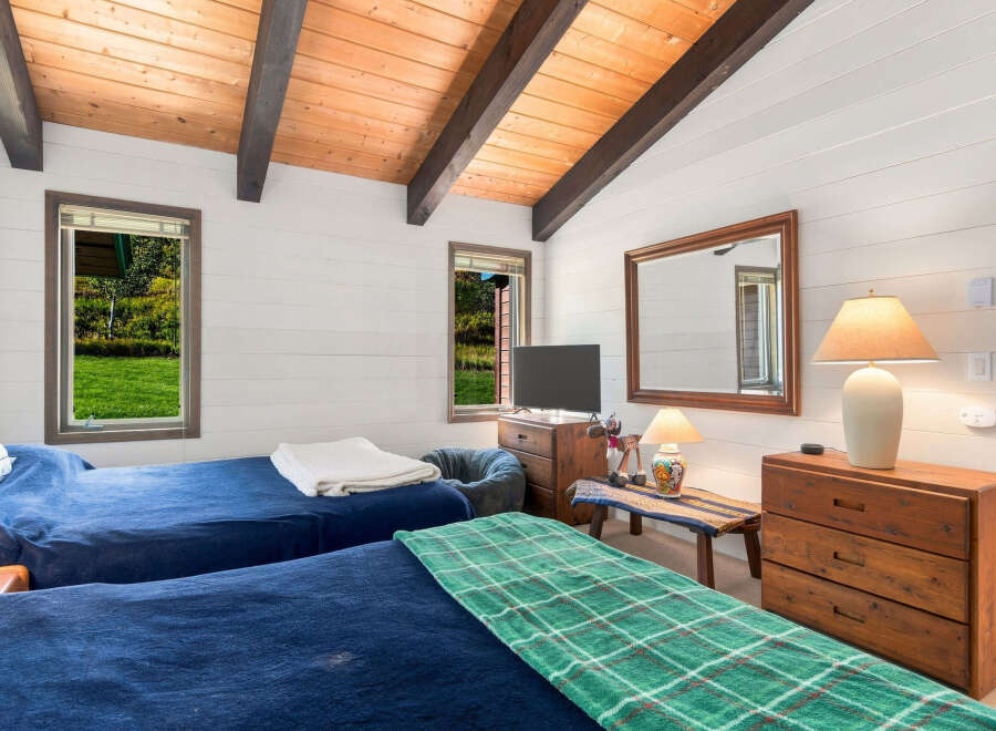 This charming bedroom features two comfortable beds dressed in deep blue linens, perfect for a restful night's sleep.