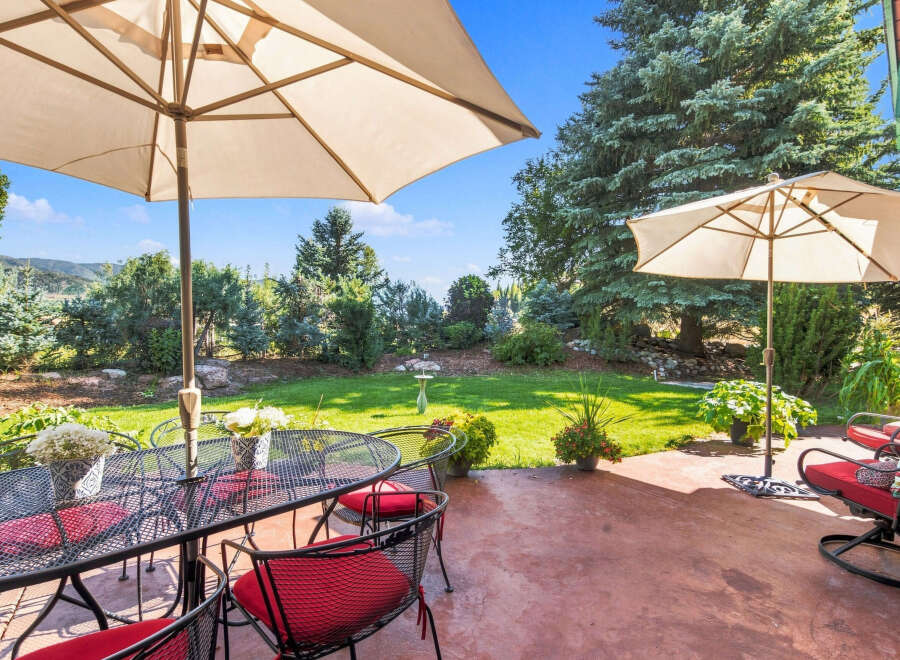 Enjoy outdoor living with this charming patio featuring a dining set under a large umbrella, perfect for al fresco meals.