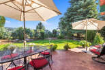 Enjoy outdoor living with this charming patio featuring a dining set under a large umbrella, perfect for al fresco meals.