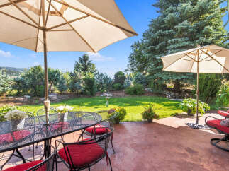 Enjoy outdoor living with this charming patio featuring a dining set under a large umbrella, perfect for al fresco meals.