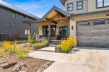Experience modern mountain living in this stunning home featuring a covered front porch with exposed beams and a cozy seating area.