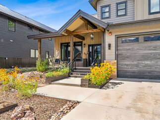 Experience modern mountain living in this stunning home featuring a covered front porch with exposed beams and a cozy seating area.